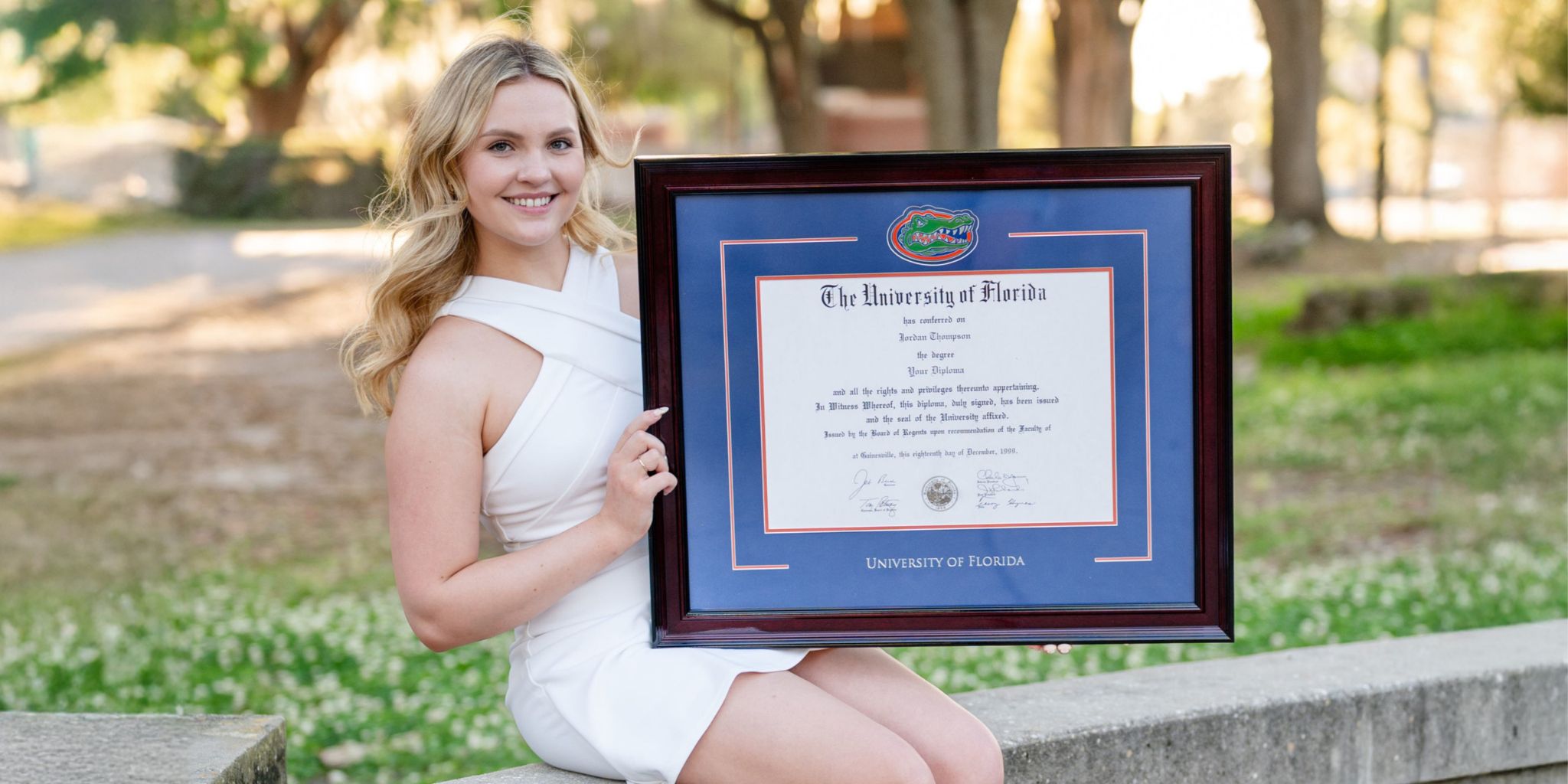 Smiling university of florida graduate holding a custom UF spirit diploma frame