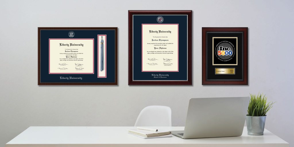 custom Liberty University diploma frames and award plaque hung on wall behind office desk