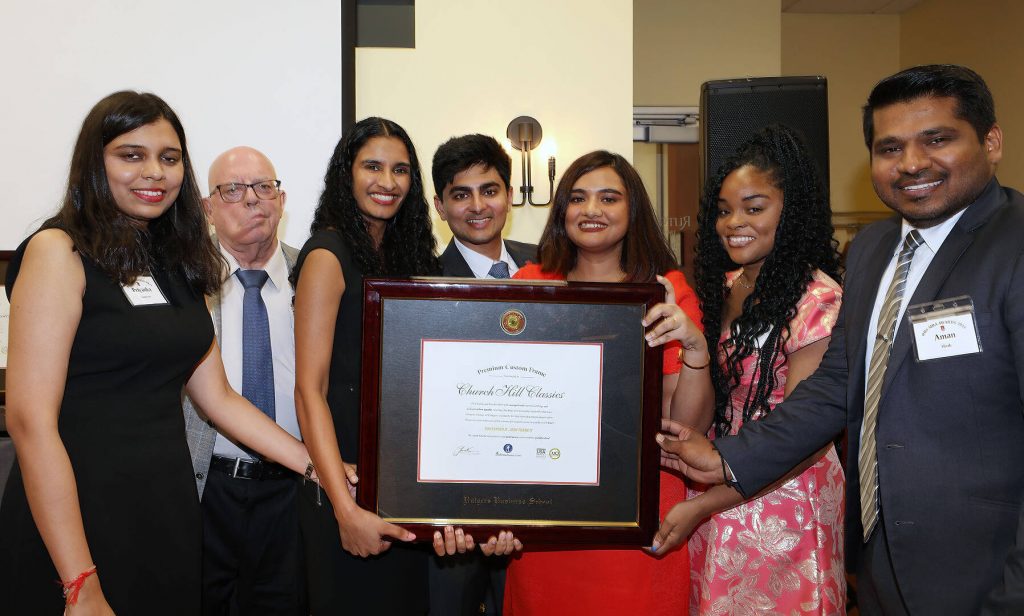 Group of students with professor holding a Rutgers Business degree frame.