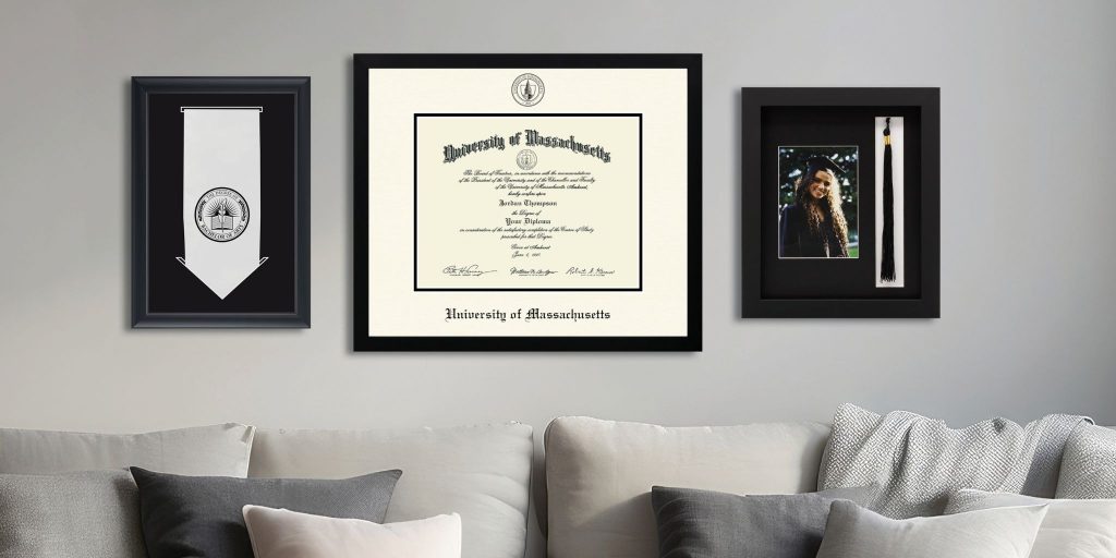 UMass diploma frame, graduation photo, and graduation stole frame on wall above couch.