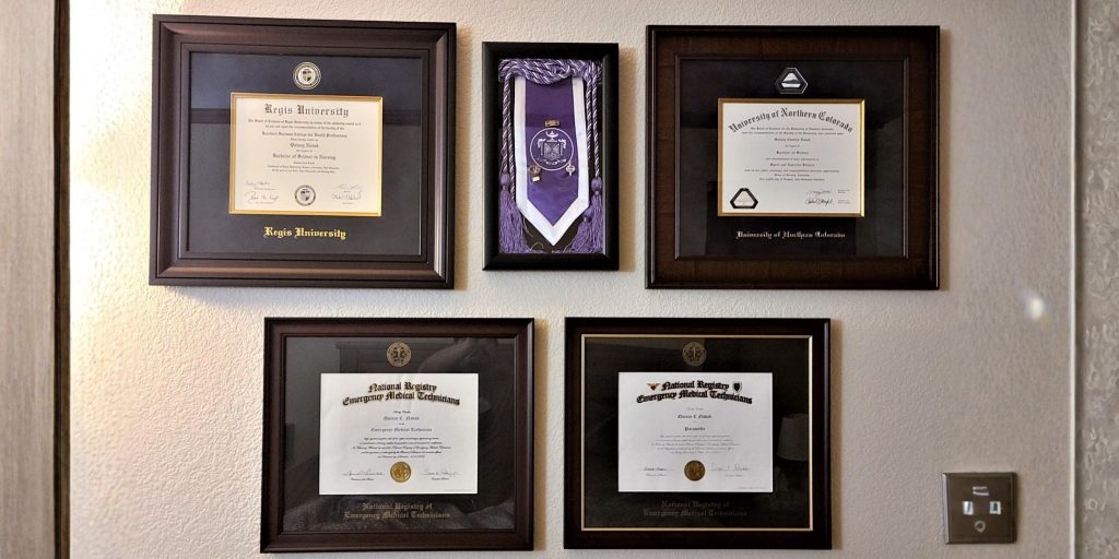 Framed degrees and certificates on an office wall.
