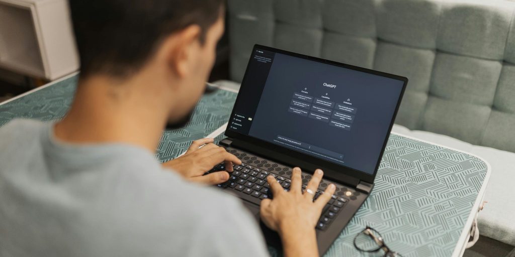 Man on laptop at desk with ChatGPT on screen.