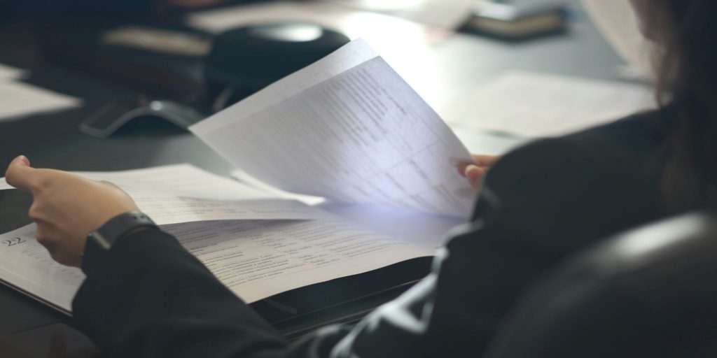 Closeup of hands leafing through documents on a desk at work.