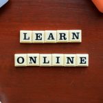 Closeup of square letters on desk that spell out LEARN ONLINE.