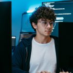 Man at desk working on two different computer screens.