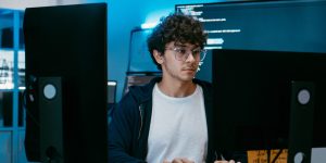 Man at desk working on two different computer screens.