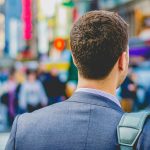Back of a businessman walking in busy city.