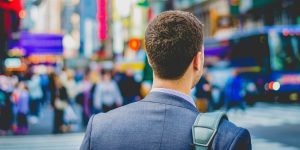 Back of a businessman walking in busy city.