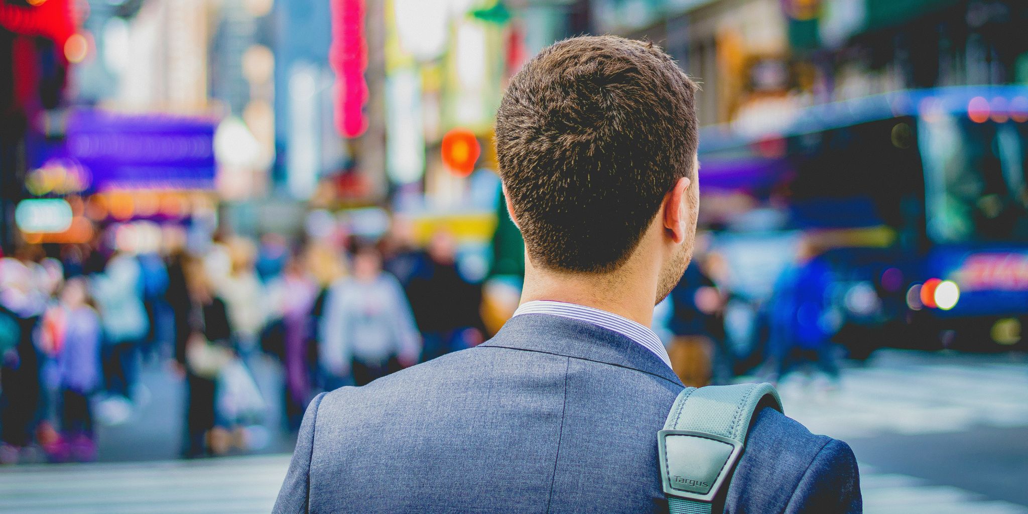 Back of a businessman walking in busy city.