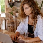 Woman sitting at table in cafe working on her laptop.