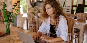Woman sitting at table in cafe working on her laptop.