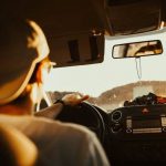Back of driver with baseball cap keeping his eyes on the road as he drives.