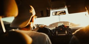 Back of driver with baseball cap keeping his eyes on the road as he drives.