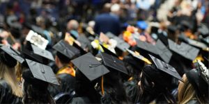 A sea of black grad caps, some with designs on them, during a commencement ceremony.
