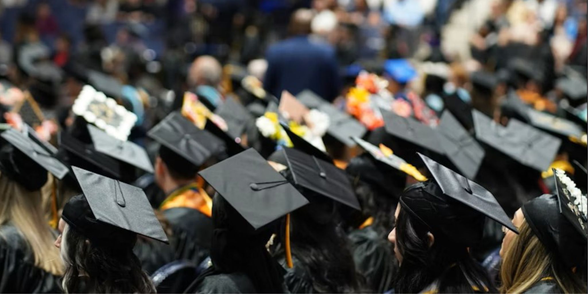 A sea of black grad caps, some with designs on them, during a commencement ceremony.