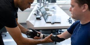 A doctor helping to fit a patient with a prosthetic arm.