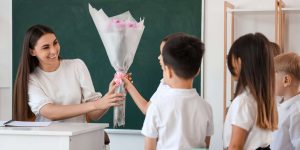 students handing teacher a gift of flowers