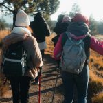 Hikers wearing backpacks, jackets, and knit caps walking on a hiking chair.
