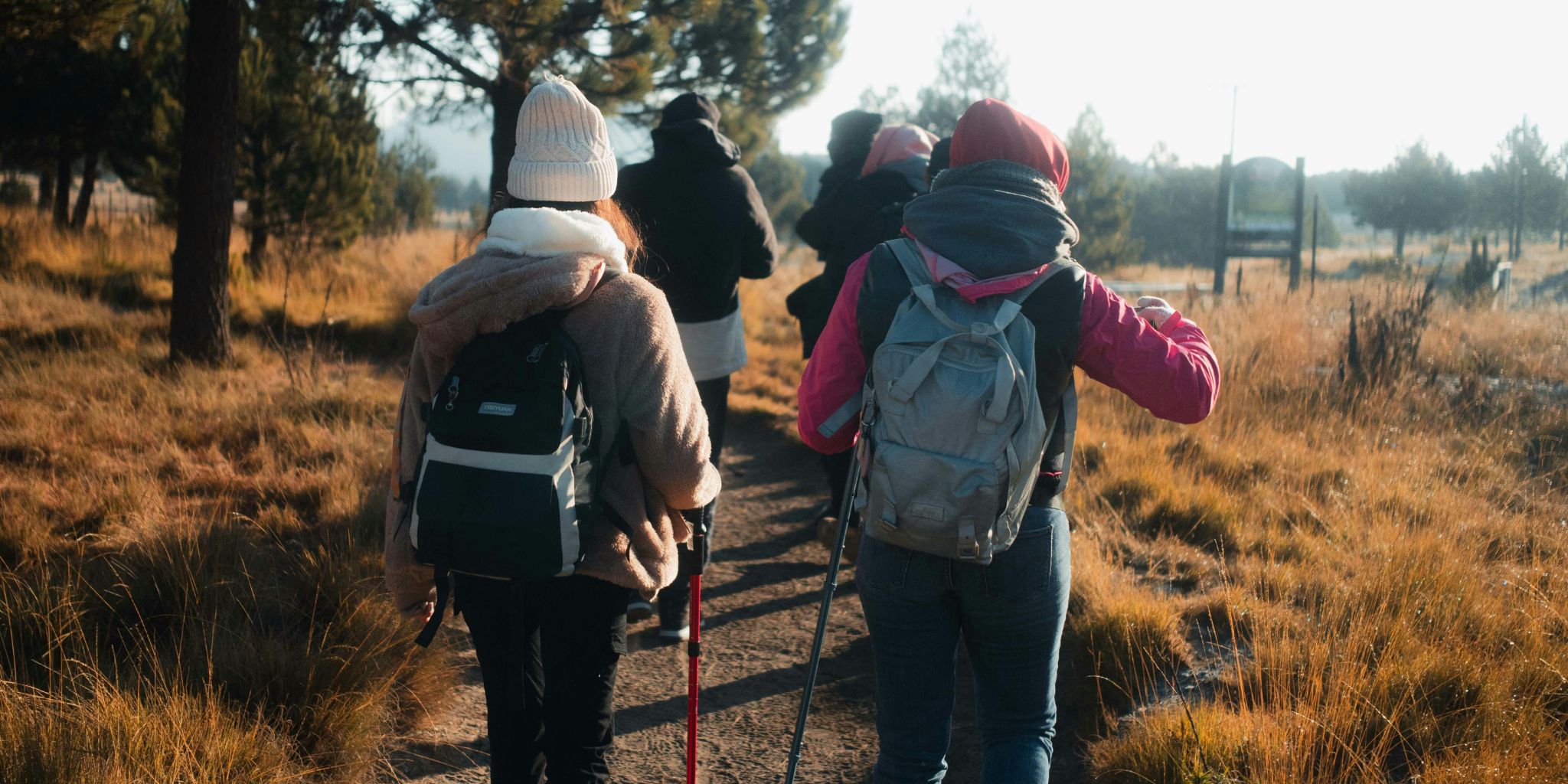 Hikers wearing backpacks, jackets, and knit caps walking on a hiking chair.
