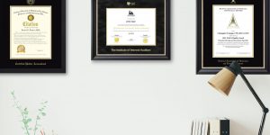 Office wall with CPA certificate frame, Institute of Internal Auditors certificate frame, and NAIFA certificate frame with desk lamp and books in photo.