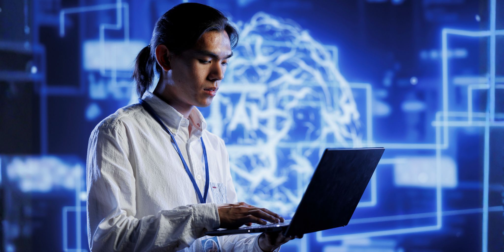Person holding laptop and wearing lanyard in front of large screen behind them featuring AI tech graphic.