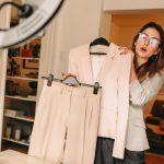 Woman in living room in front of web camera holding business suit on camera and talking about the clothing.