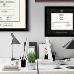 Home office with white desks and black chairs with University of Oregon diploma frame and State of Oregon certificate frame on wall.