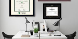 Home office with white desks and black chairs with University of Oregon diploma frame and State of Oregon certificate frame on wall.