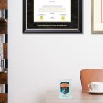 Office space featuring The Institute of Internal Auditors certificate frame and a University of Wisconsin Madison diploma frame on the wall and a Databricks digital badge on the desk next to a white coffee cup.