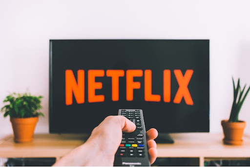 hand clicking remote in front of Netflix screen