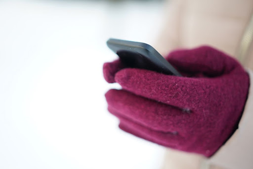 gloved hands in winter holding cell phone