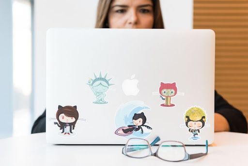 girl working on laptop with cartoon stickers on it