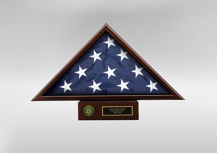 Triangular wooden display case showcasing a folded American flag with an engraved military nameplate and service emblem.