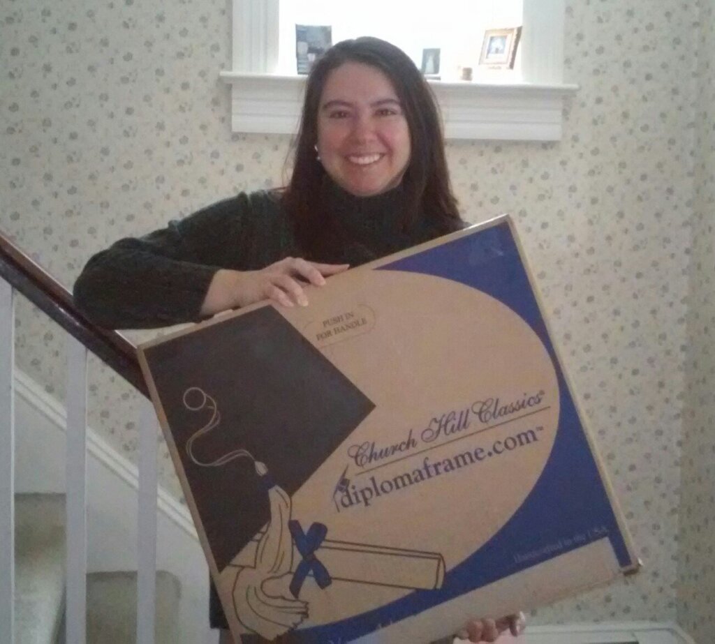 Smiling woman holding a Church Hill Classics diploma frame box