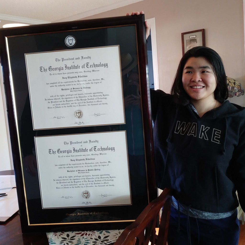 Smiling grad holding her Georgia Tech double diploma frame