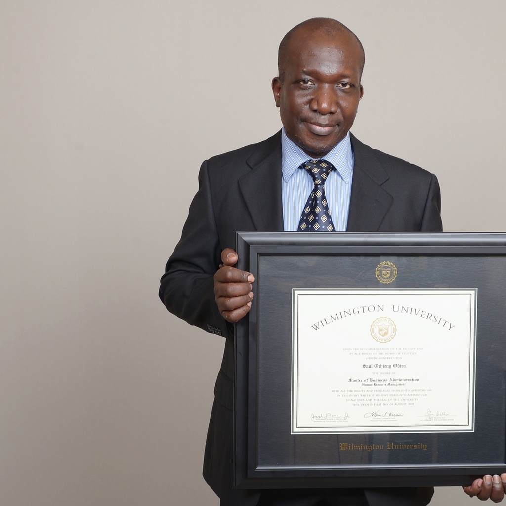 man in suit holding his wilmington university MBA frame