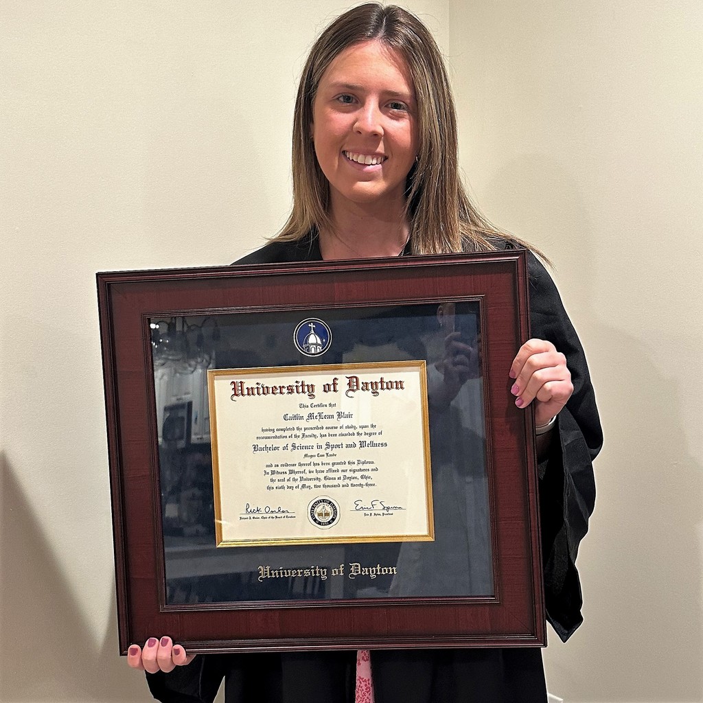 smiling graduate holding university of dayton diploma frame