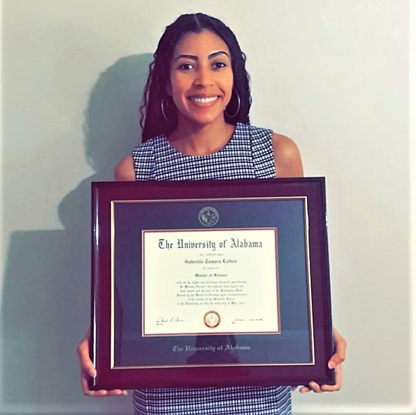 smiling woman holding University of Alabama degree frame