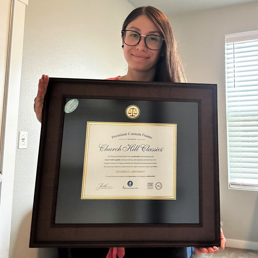 woman with glasses holding law degree frame