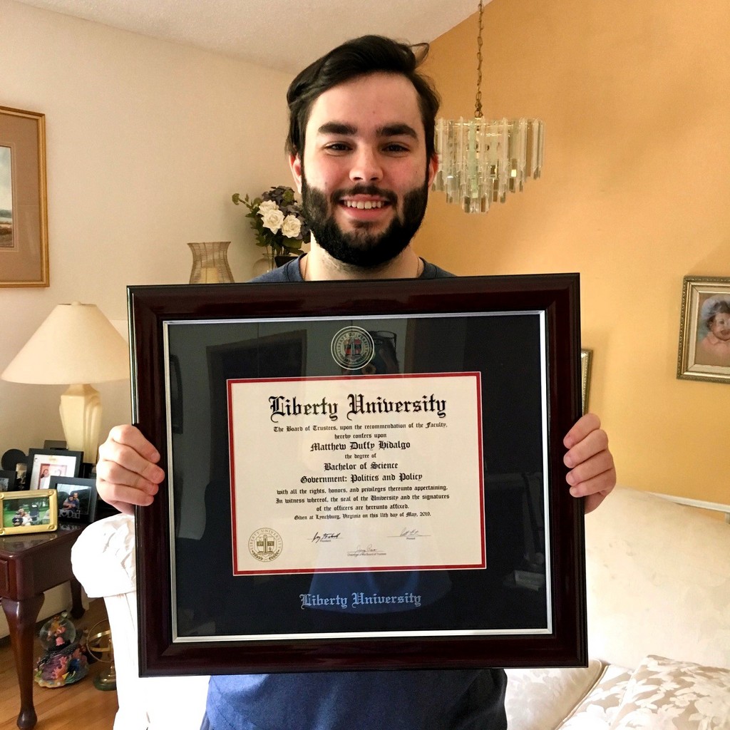man with beard smiling and holding Liberty University degree frame