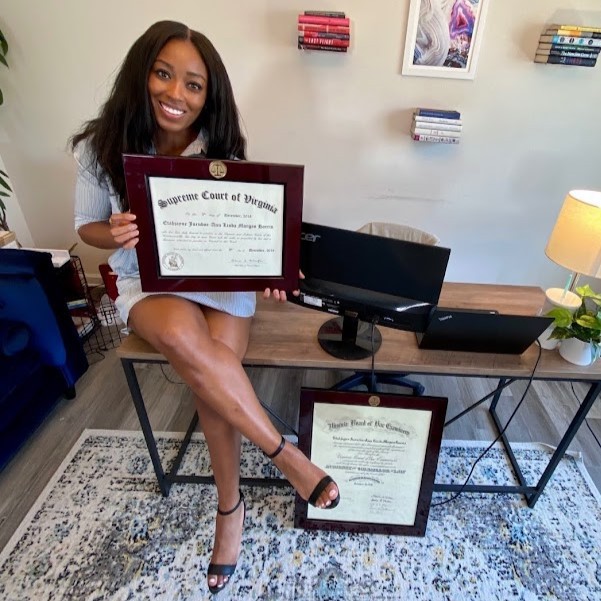 Lawyer sitting on desk holding her law degree frame