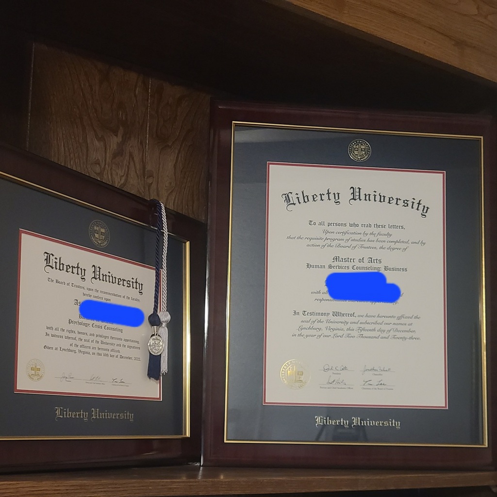 two Liberty University diploma frames on bookshelf