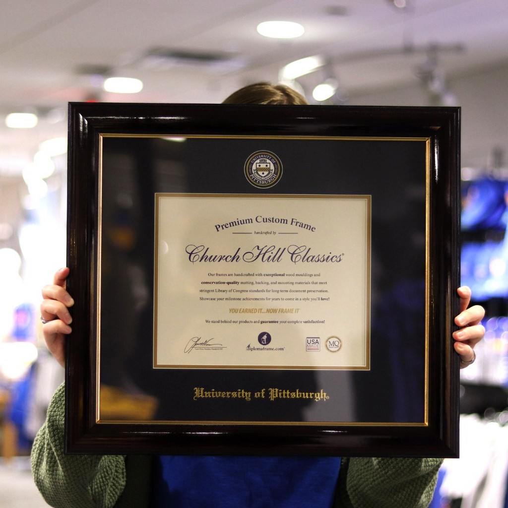 person hiding behind UPitt diploma frame with masterpiece medallion