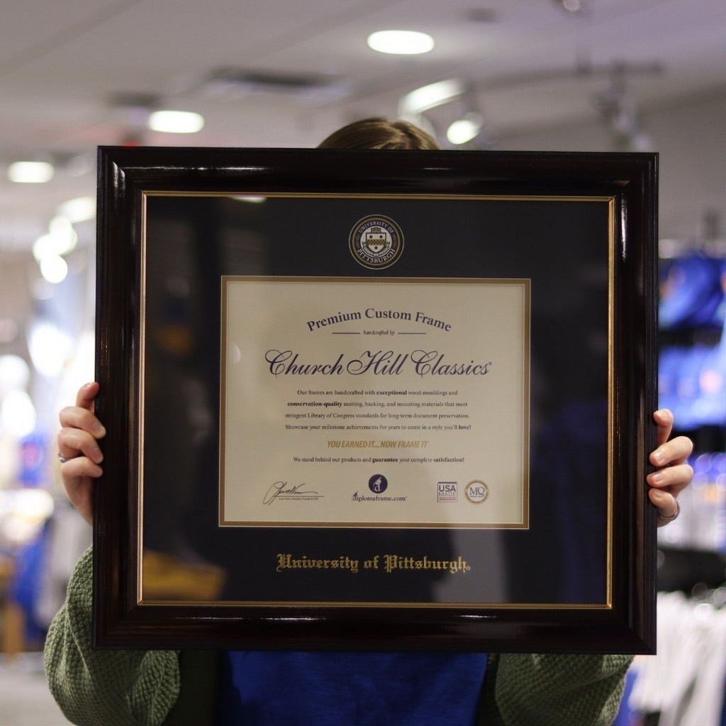 Person in bookstore holding Pitt diploma frame in front of his face