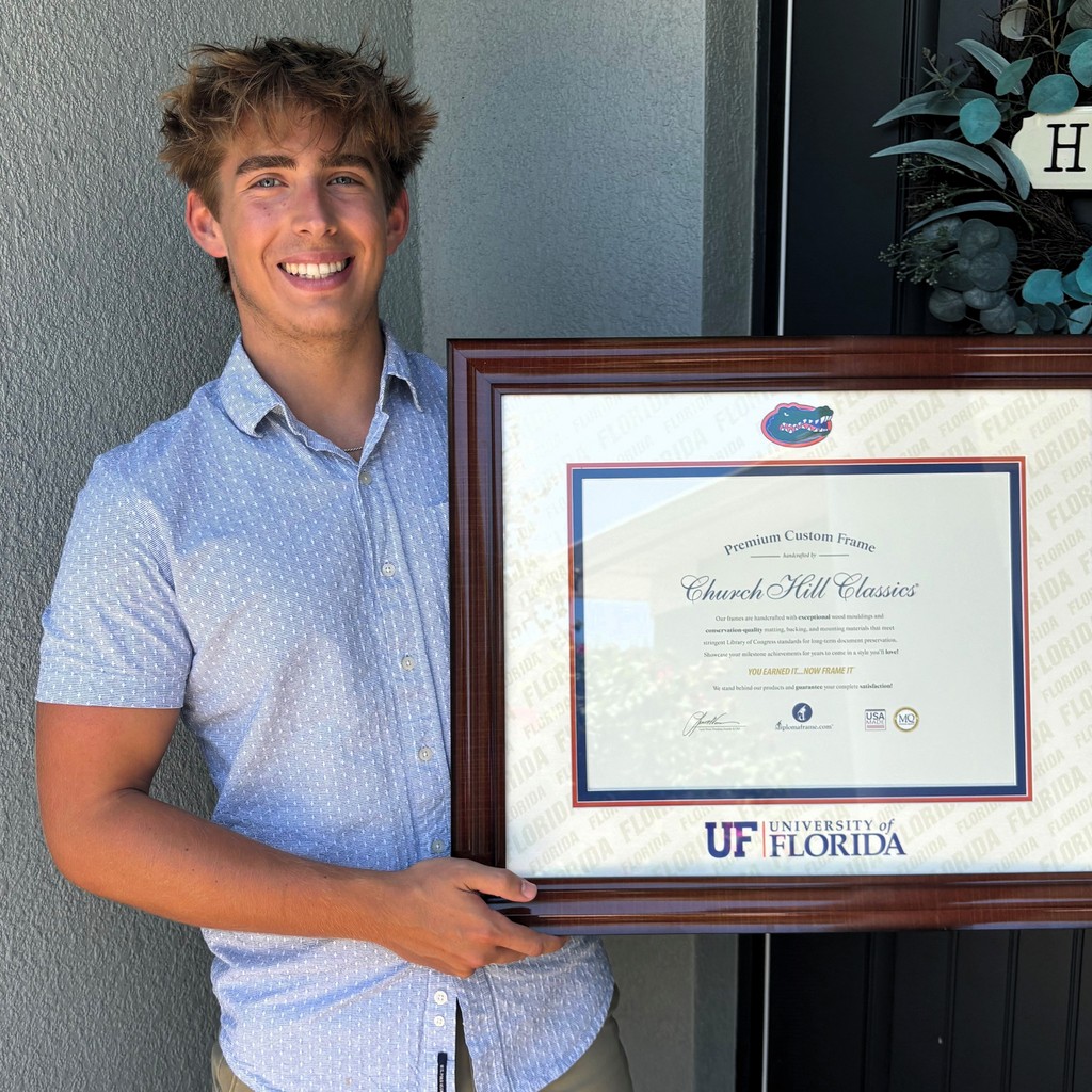 smiling man holding University of Florida Gators diploma frame