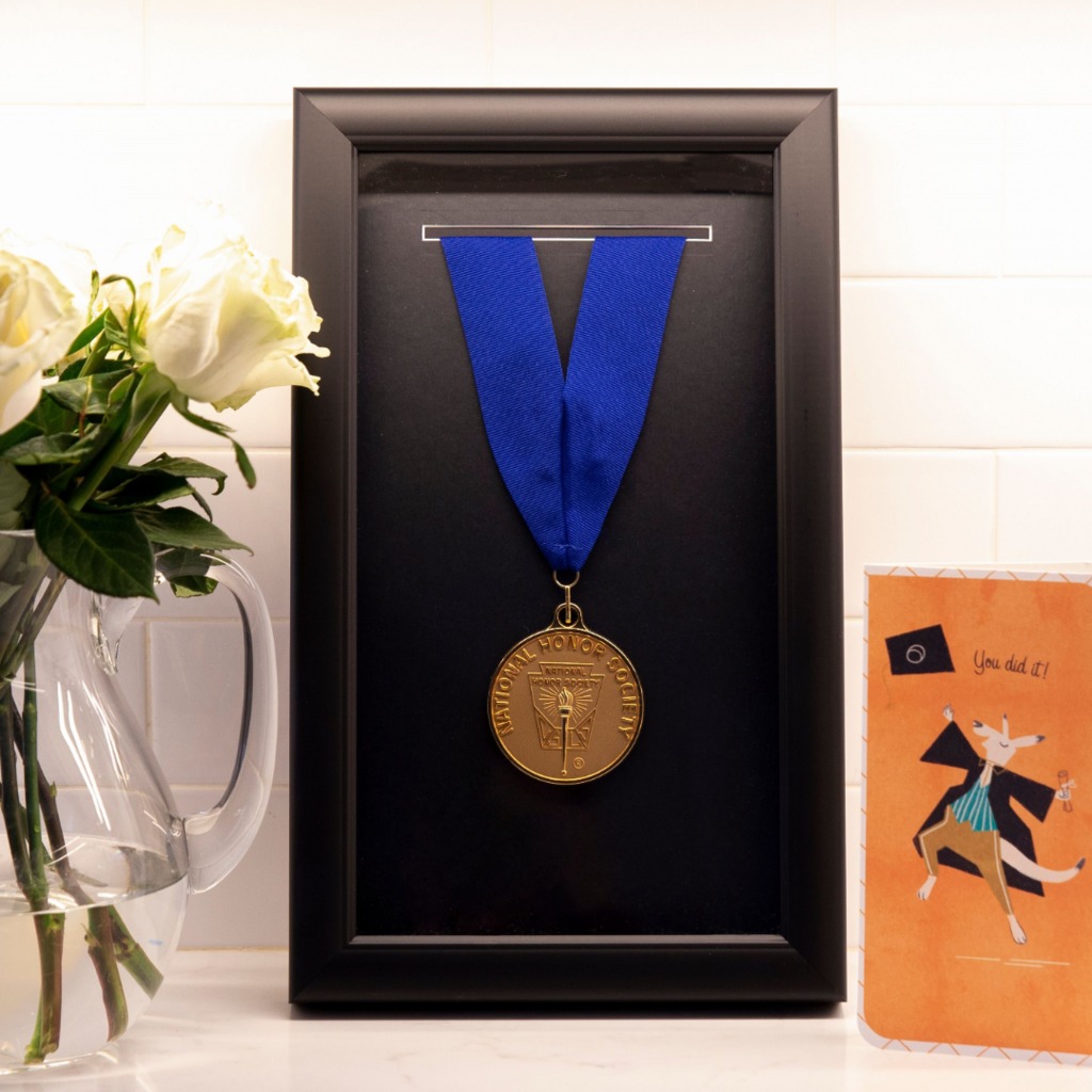 national honor society medal hanging in black shadow box frame