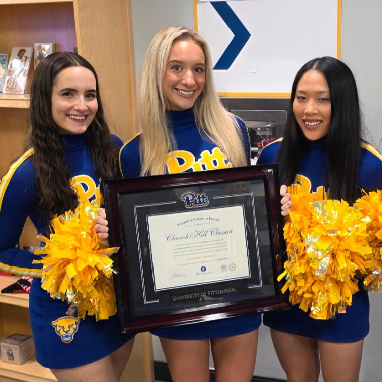 Pitt cheerleaders with pompoms holding UPitt diploma frame in bookstore