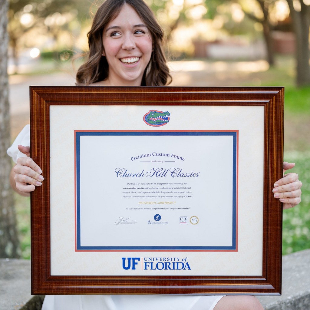 Closeup of smiling woman holding University of Florida diploma frame with UF Gator on it