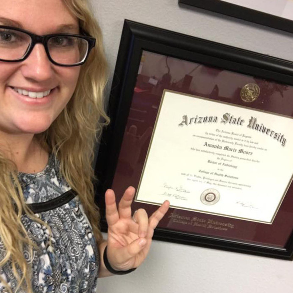 woman smiling in front of an Arizona State University diploma frame