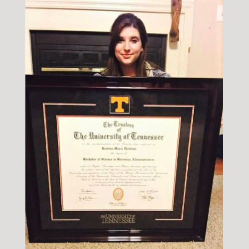woman smiling and sitting behind a The University of Tennessee Knoxville spirit diploma frame